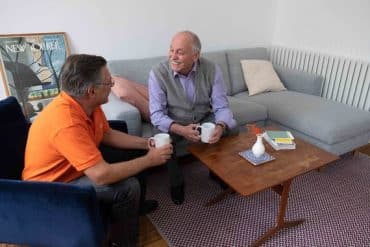 Une aide à domicile prend le thé avec un bénéficiaire en perte d'autonomie