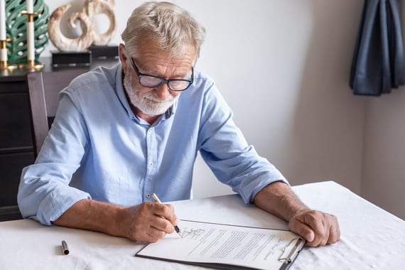 Un senior en chemise entrain de faire un testament olographe