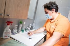 Un auxiliaire de vie réalise une aide au ménage chez un bénéficiaire